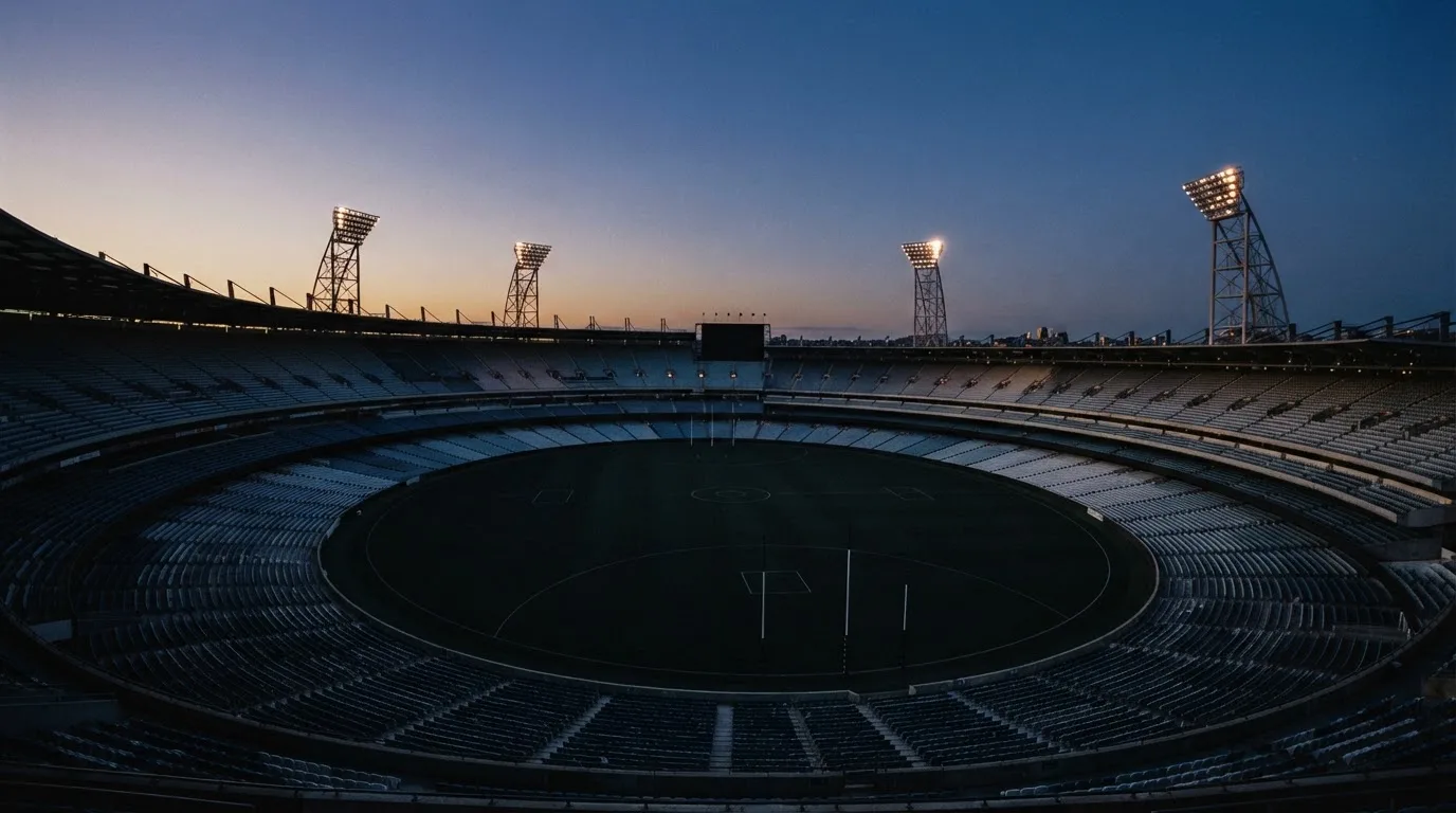 An empty football stadium with floodlight masts at dusk
