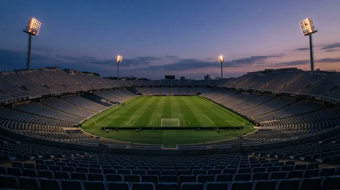 An empty football stadium with floodlight masts at dusk