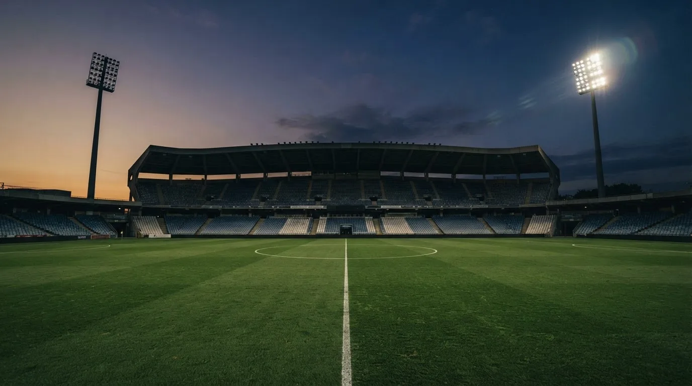 An empty football stadium with floodlight masts at dusk