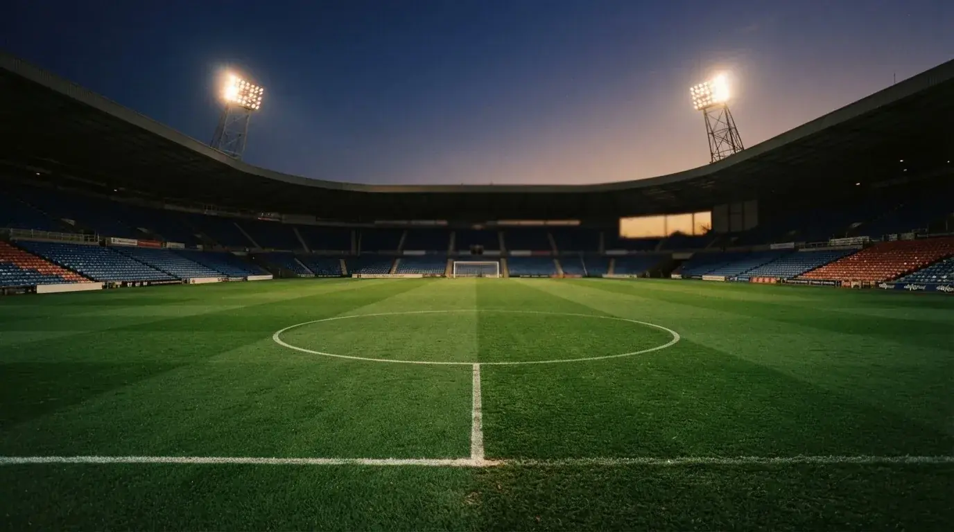 An empty football stadium with floodlight masts at dusk