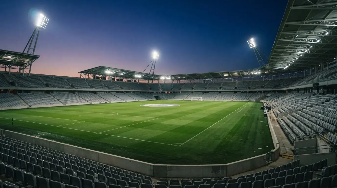 An empty football stadium with floodlight masts at dusk