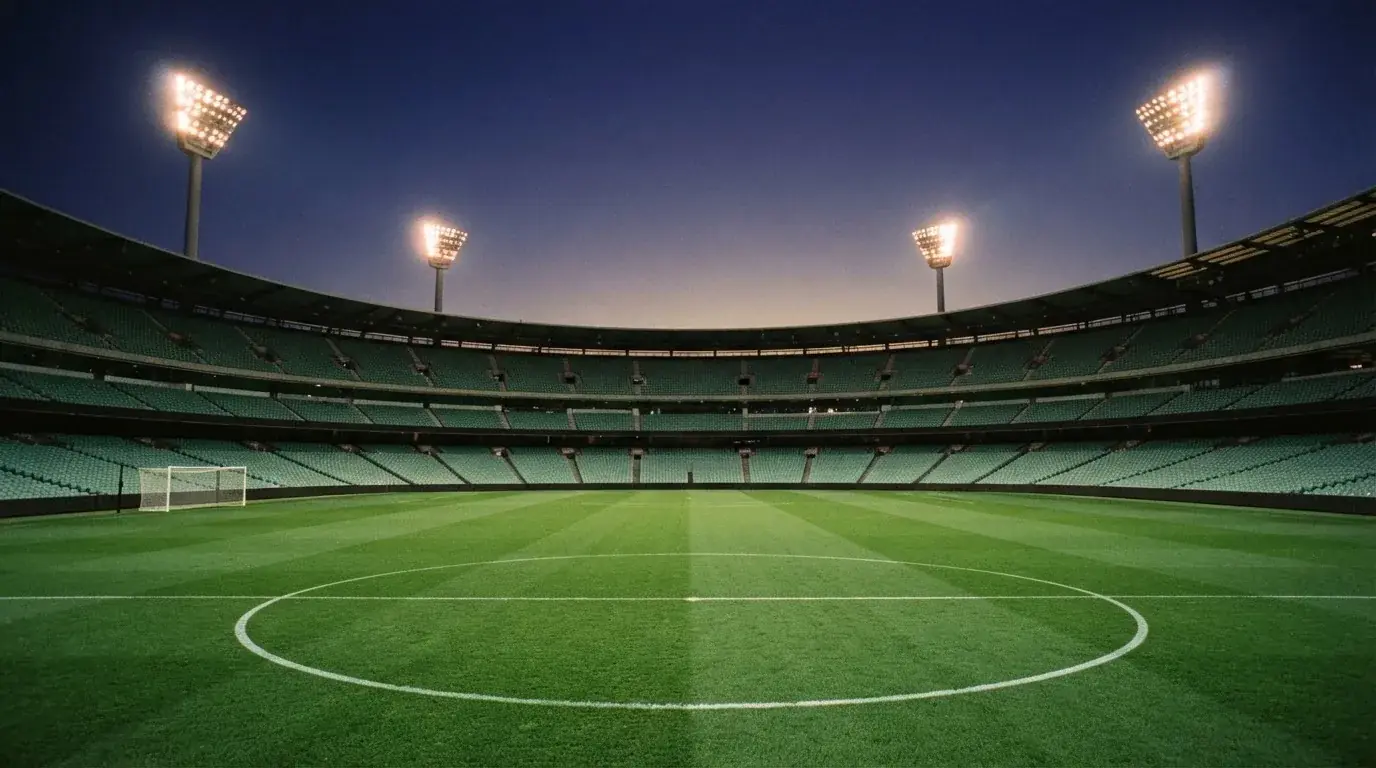 An empty football stadium with floodlight masts at dusk