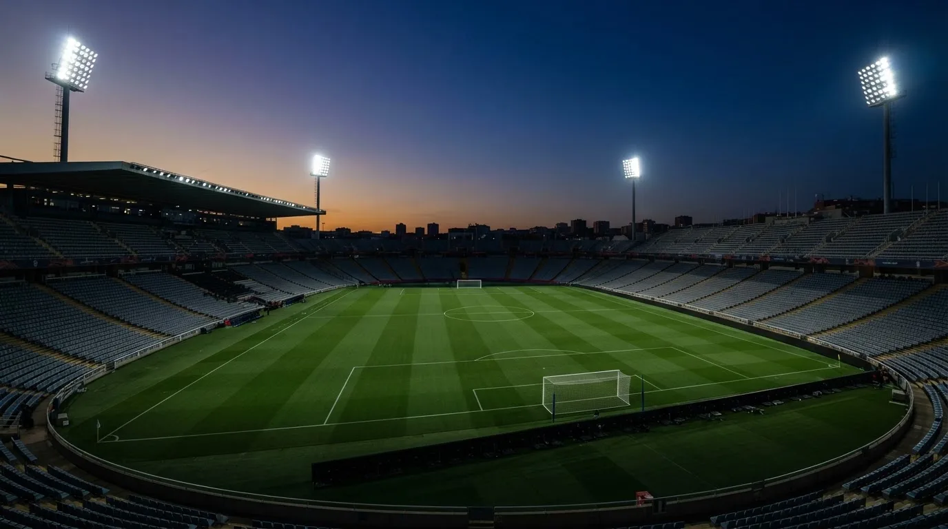 An empty football stadium with floodlight masts at dusk