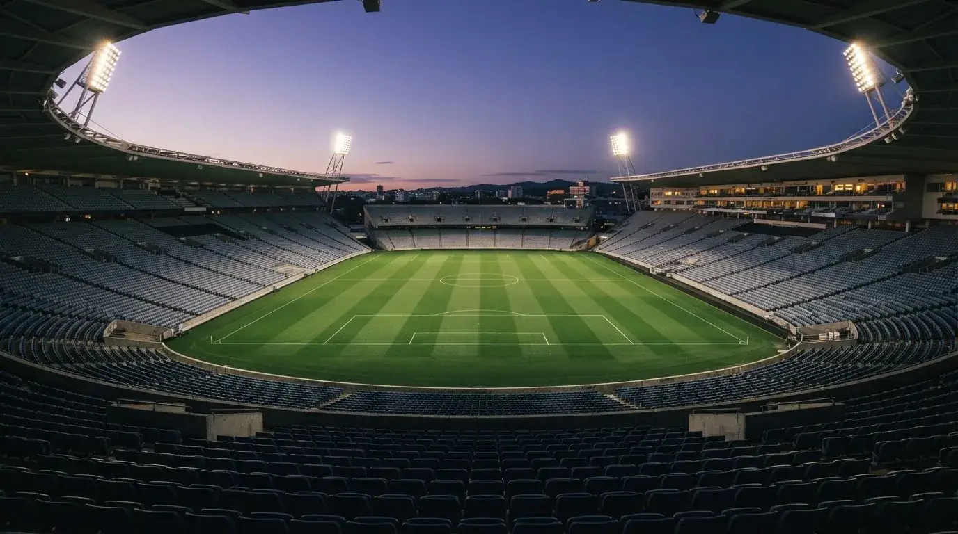 An empty football stadium with floodlight masts at dusk