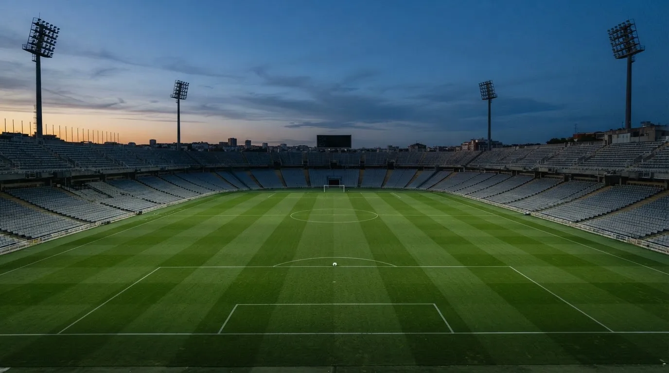 An empty football stadium with floodlight masts at dusk