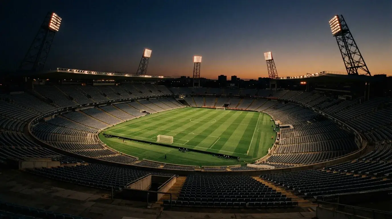 An empty football stadium with floodlight masts at dusk