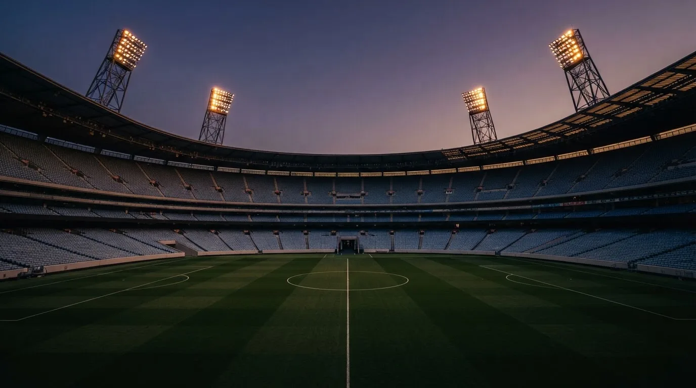 An empty football stadium with floodlight masts at dusk