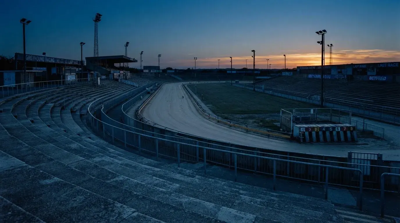 An empty football stadium with floodlight masts at dusk