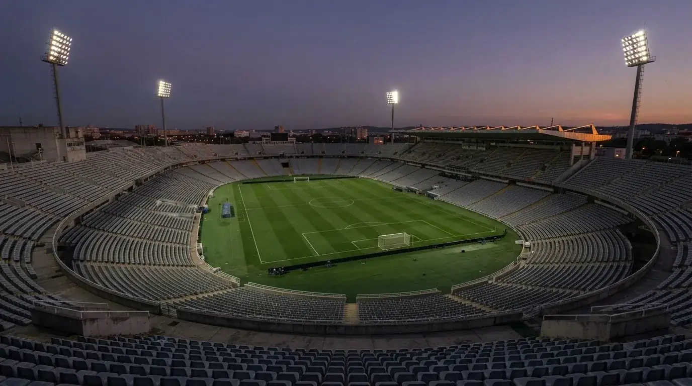 An empty football stadium with floodlight masts at dusk
