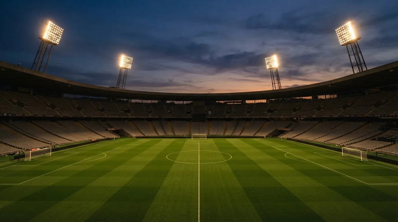 An empty football stadium with floodlight masts at dusk