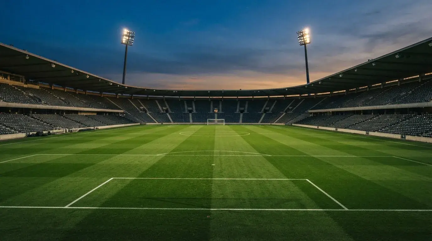 An empty football stadium with floodlight masts at dusk