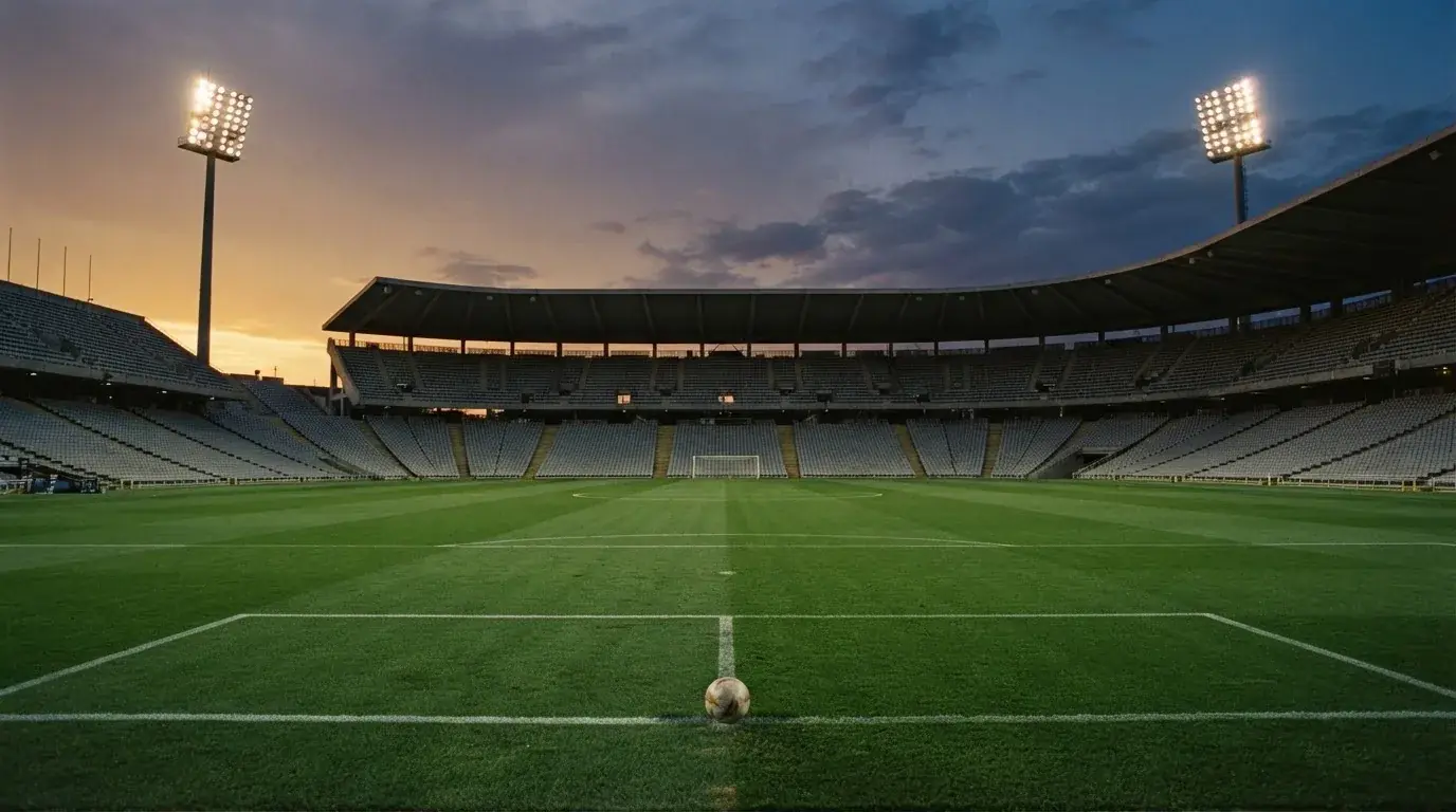 An empty football stadium with floodlight masts at dusk