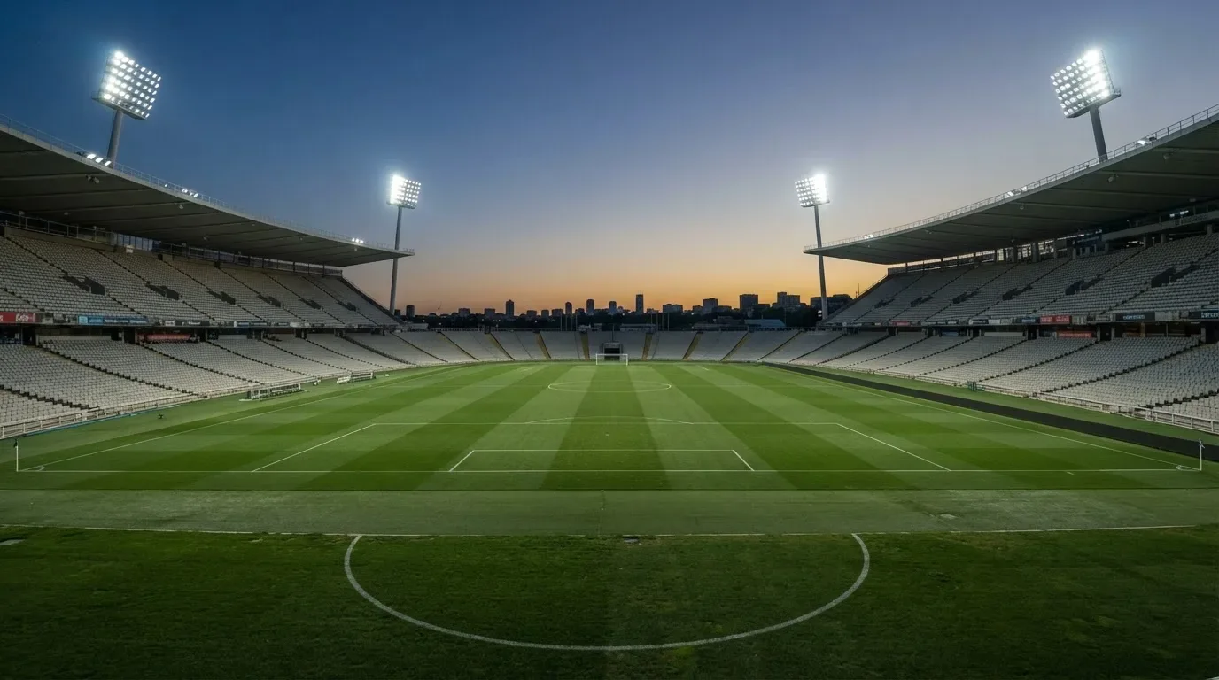 An empty football stadium with floodlight masts at dusk
